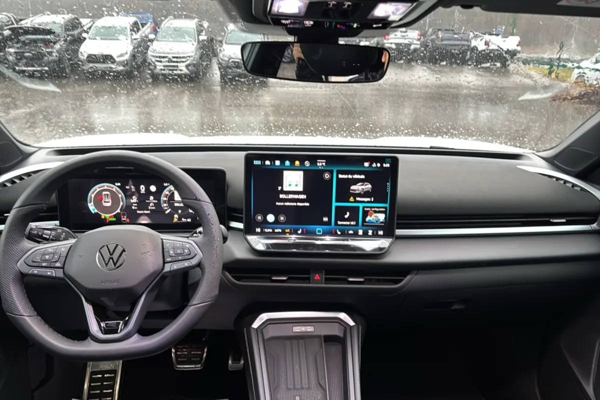 Vue intérieure frontale du tableau de bord du Volkswagen T-Roc blanc, avec écran tactile et volant multifonctions cuir.