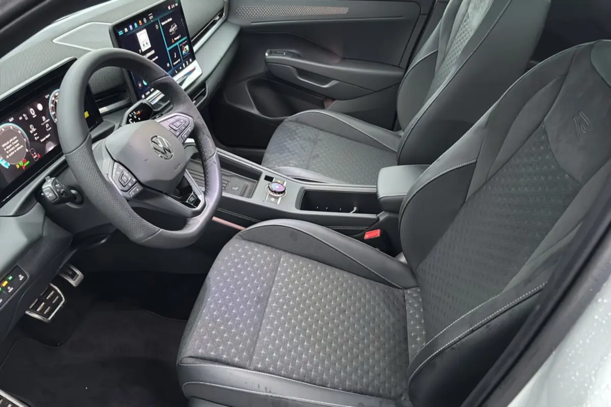 Vue intérieure côté conducteur du Volkswagen T-Roc 2026, sièges tissu noir avec surpiqûres et volant cuir multifonctions.