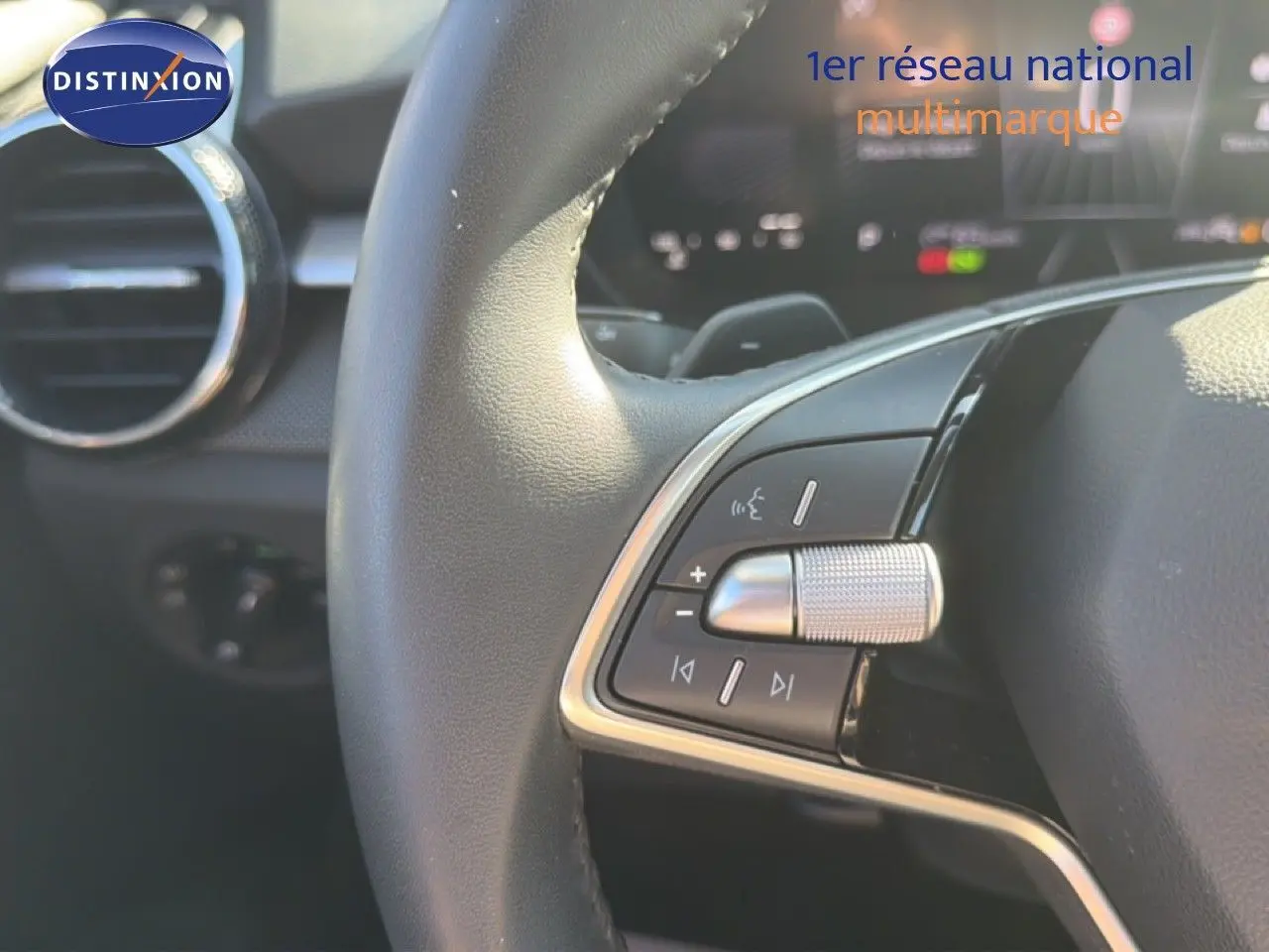 Gros plan sur les commandes au volant cuir de la Skoda Fabia 2025, avec détails métalliques et tableau de bord flou.