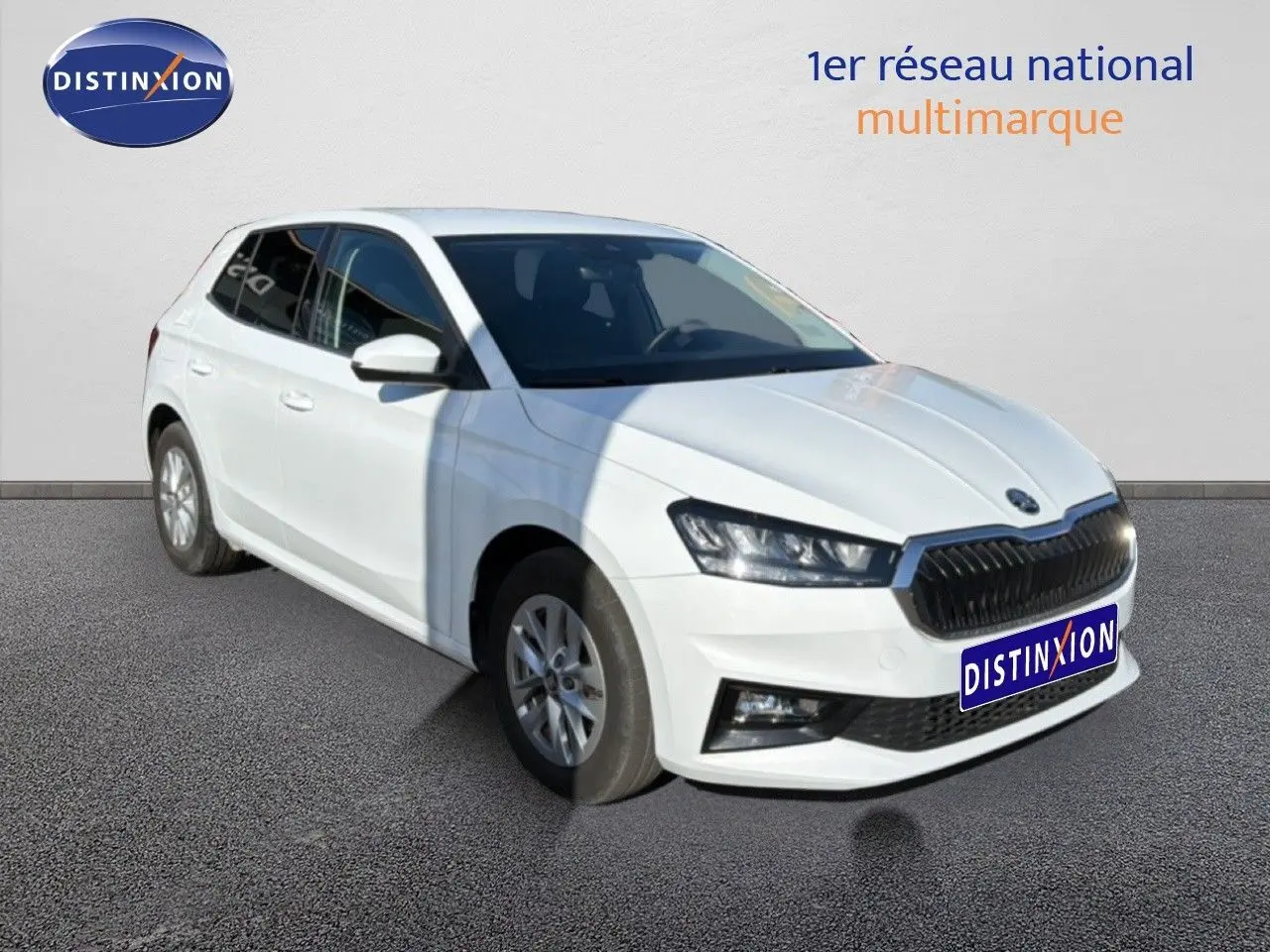 Vue 3/4 avant droite d'une Skoda Fabia blanche avec calandre noire et jantes alliage, sur fond neutre extérieur.