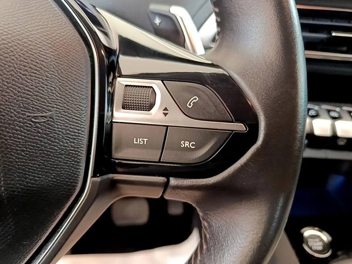 Gros plan sur les commandes gauche du volant cuir noir du Peugeot 3008 2022, avec bouton appel et molette de réglage.