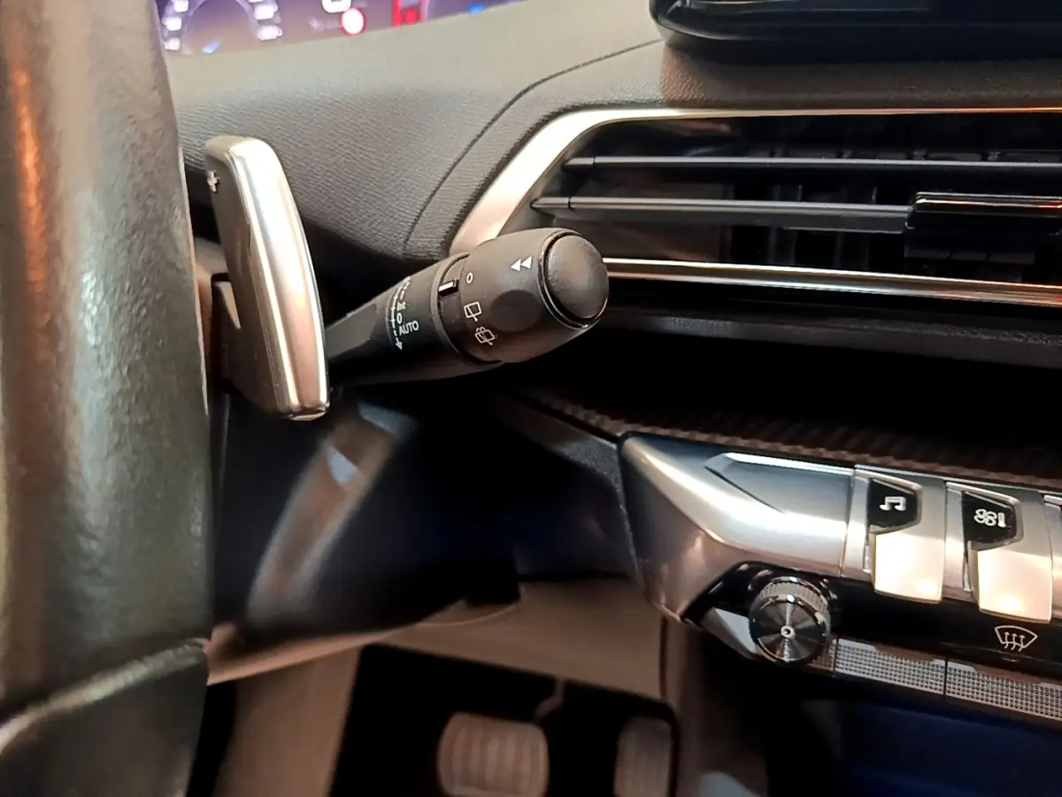 Détail intérieur du volant et commande d’essuie-glace du Peugeot 3008 bleu, avec tableau de bord et aérateurs visibles.