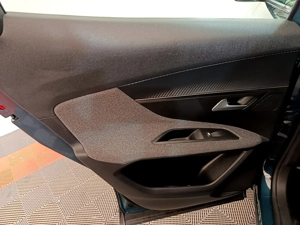 Vue rapprochée de la porte avant gauche du Peugeot 3008 bleu 2022, avec insert décoratif et poignée argentée.