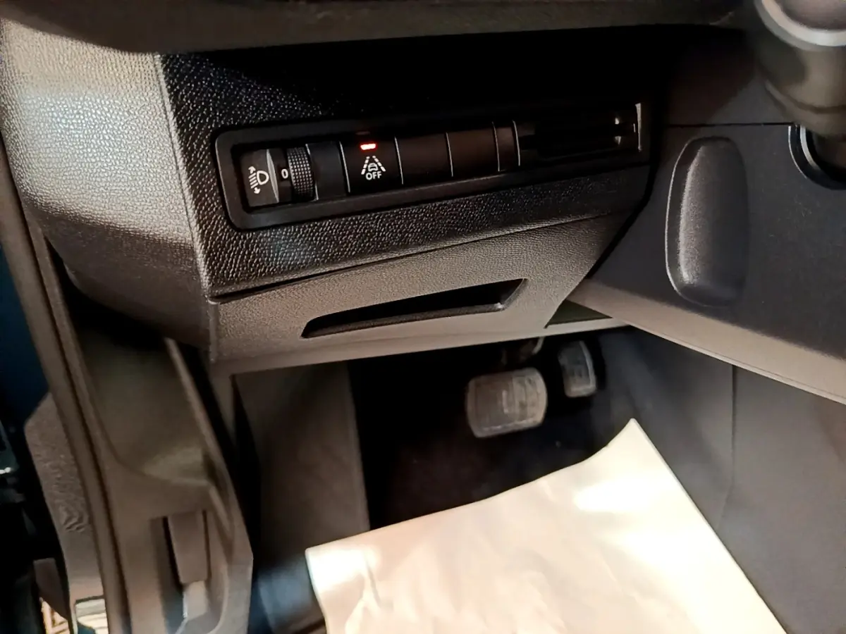 Vue intérieure côté conducteur du Peugeot 3008 bleu 2022, avec commandes d'éclairage et pédales visibles.