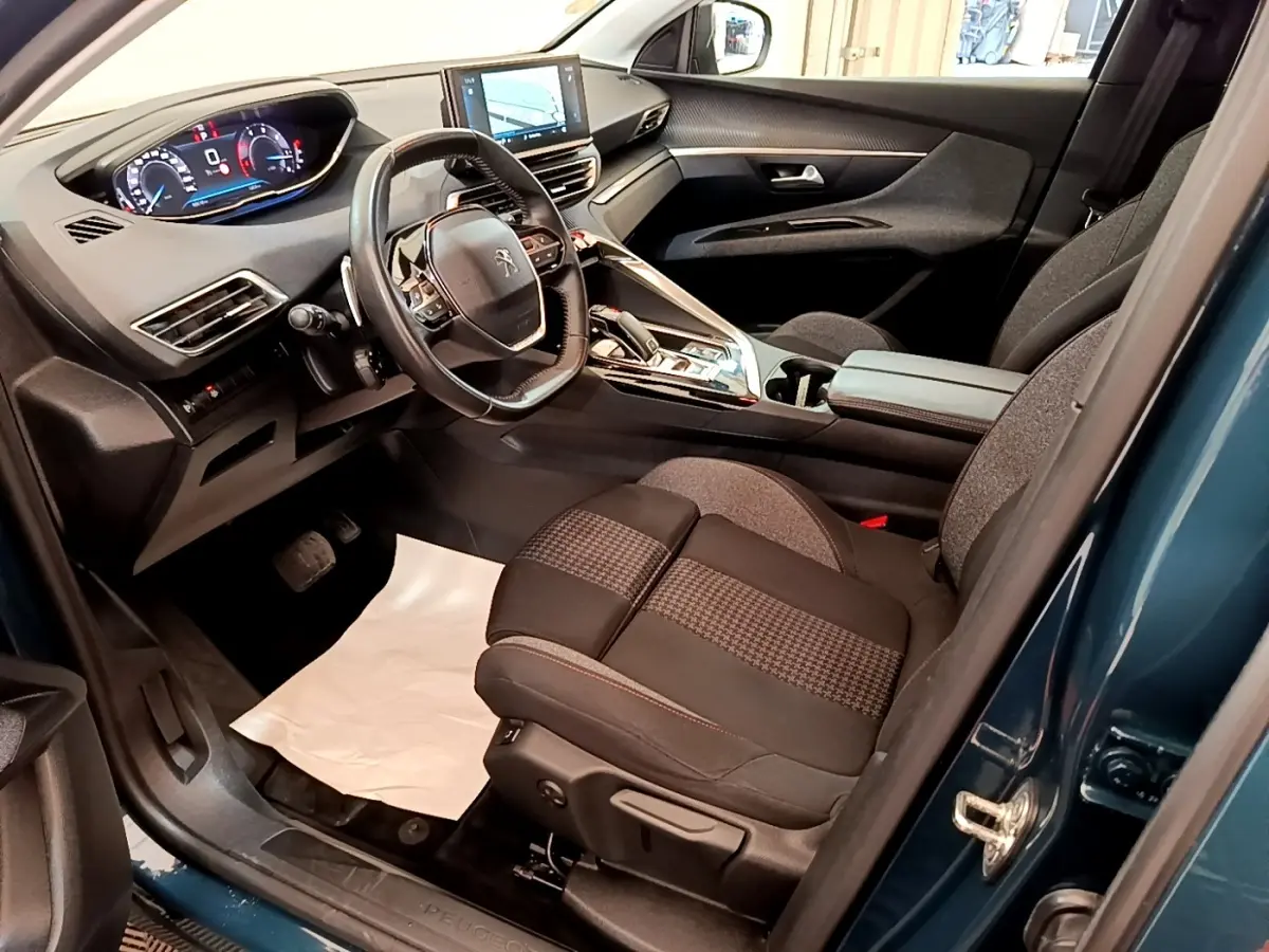 Vue intérieure côté conducteur du Peugeot 3008 bleu 2022, montrant le tableau de bord digital et le volant cuir multifonctions.