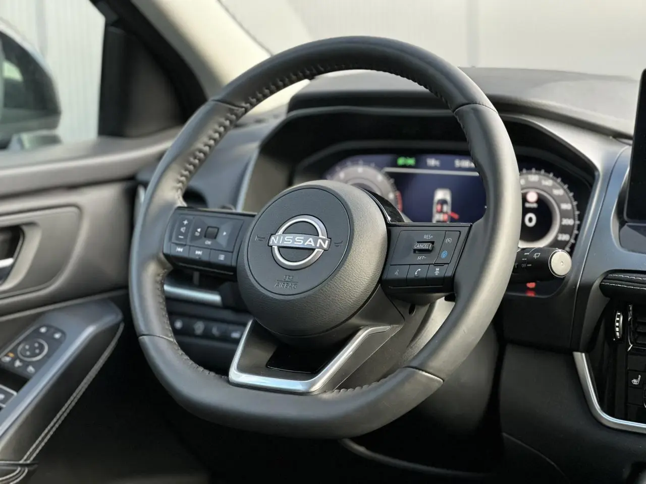 Volant cuir noir Nissan Qashqai 2025 vu de face avec commandes intégrées et tableau de bord numérique flou.