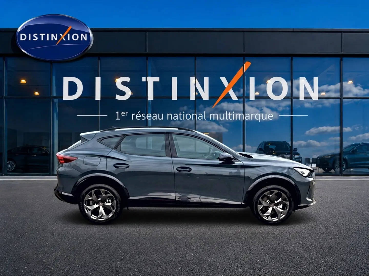 Vue latérale droite d’un CUPRA Formentor bleu fjord 2026 avec jantes 18 pouces devant une vitrine Distinxion.
