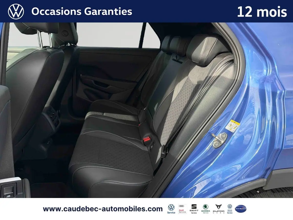 Vue intérieure arrière côté droit du Volkswagen T-Roc bleu, montrant les sièges arrière en cuir noir avec inserts tissu.