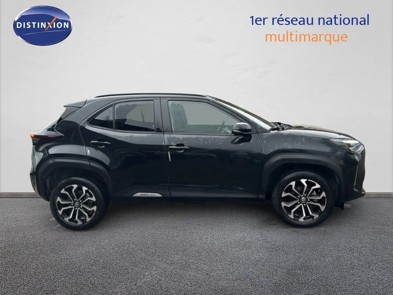 Profil côté gauche d'un Toyota Yaris Cross 116h Design noir 2023 avec jantes bi-ton et lignes robustes.