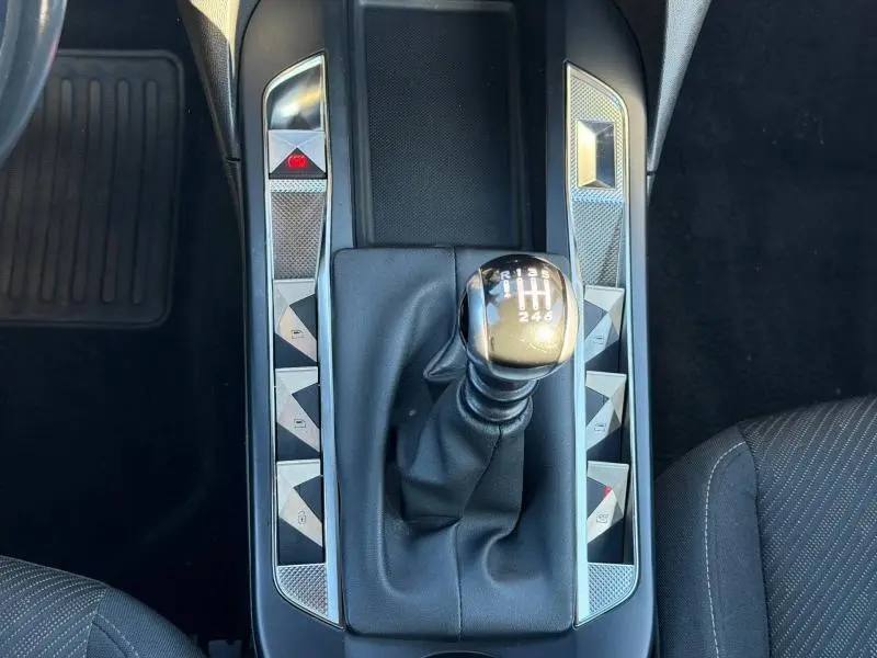 Vue plongeante sur la console centrale noire du DS3 Crossback 2020, avec levier de vitesse manuel et boutons argentés triangulaires.
