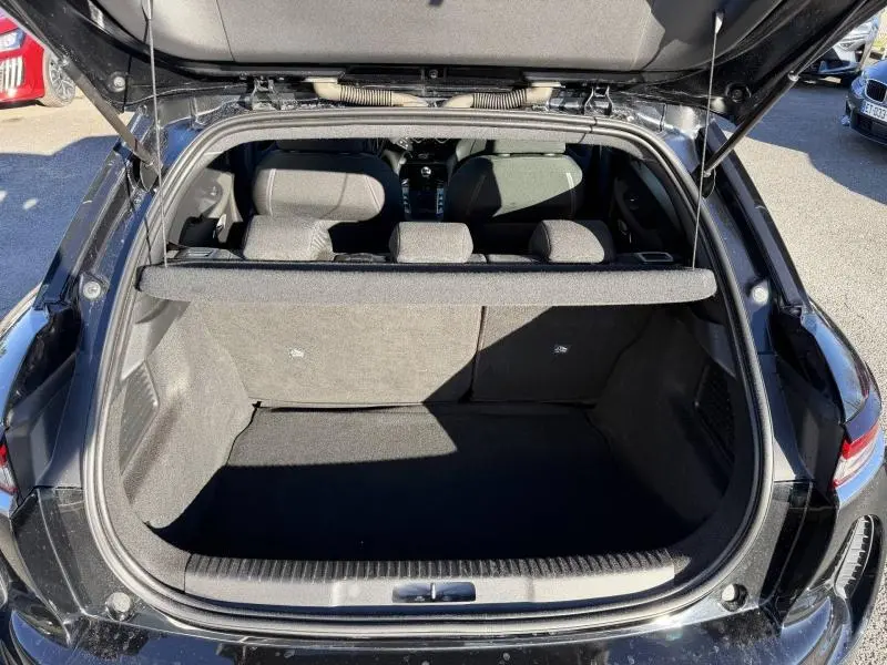 Vue arrière du coffre ouvert d'une DS3 Crossback noire, montrant l'espace de chargement et les sièges arrière en tissu gris.