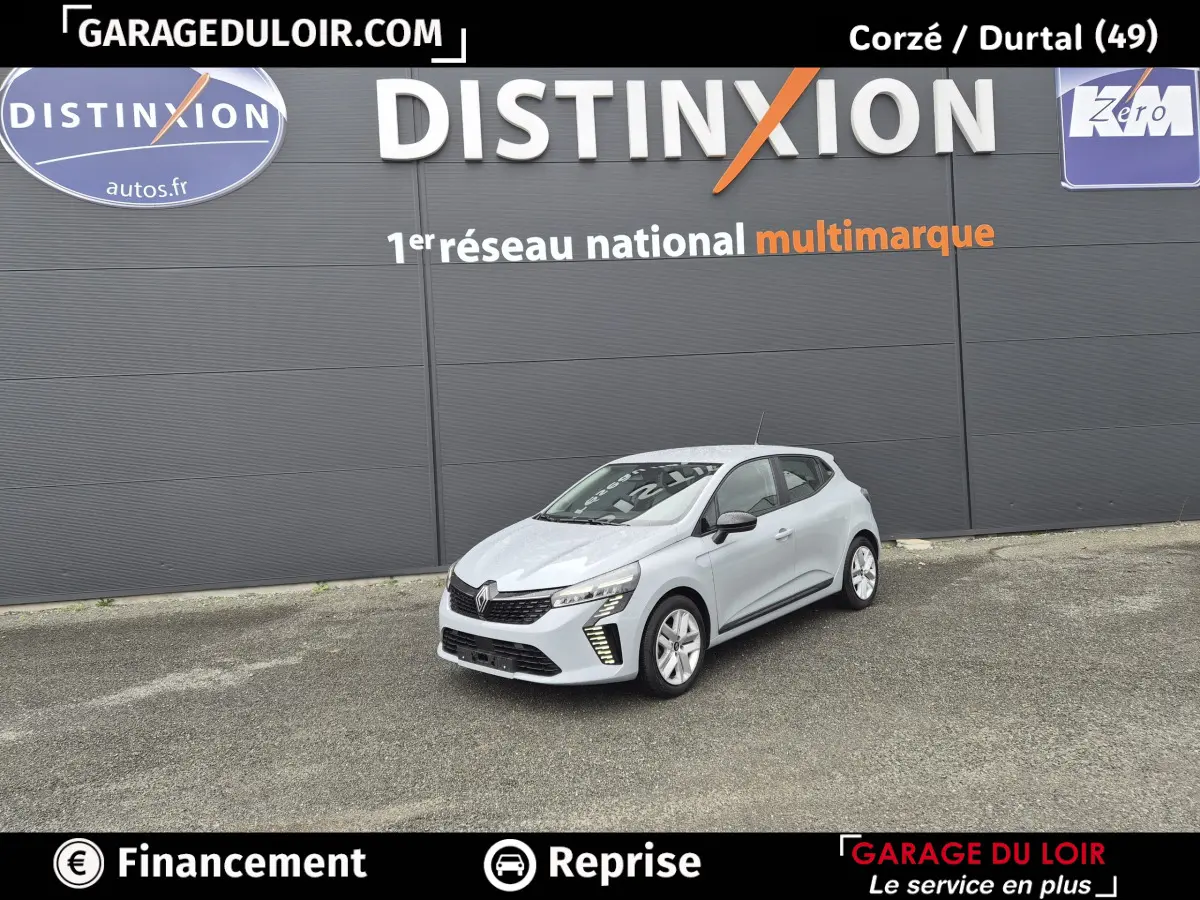 Renault Clio Evolution TCe 90 gris clair vue 3/4 avant, avec feux LED et jantes alliage devant un mur gris.