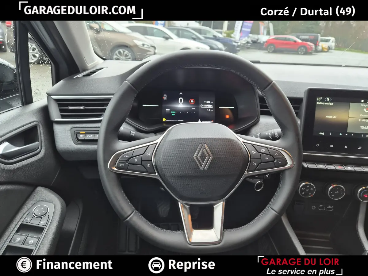 Vue intérieure centrée sur le volant cuir multifonctions de la Renault Clio gris clair avec tableau de bord numérique.