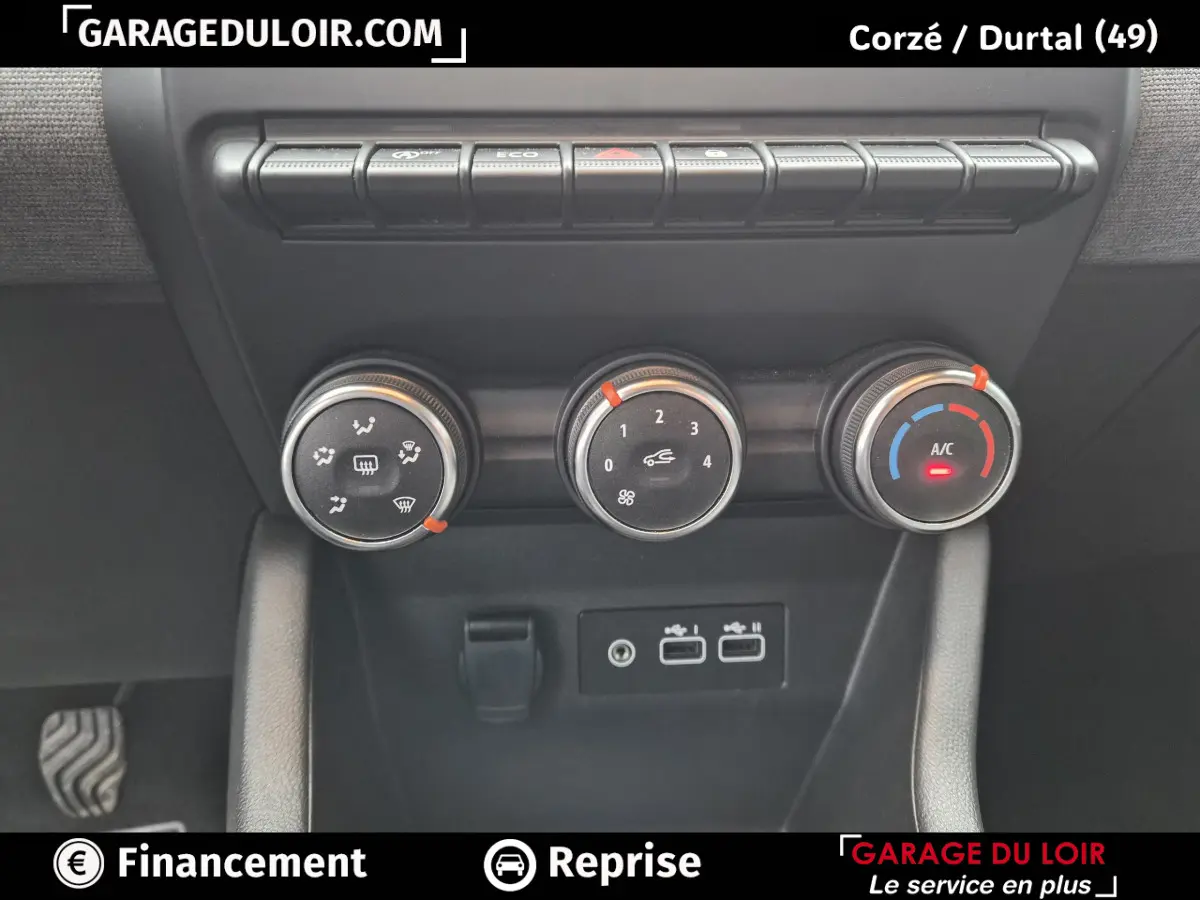 Gros plan sur les commandes de climatisation et les ports USB d'une Renault Clio gris clair, intérieur moderne et fonctionnel.