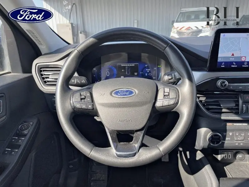 Vue intérieure centrée sur le volant cuir multifonction du Ford Kuga 2022, avec tableau de bord digital et écran tactile visible.