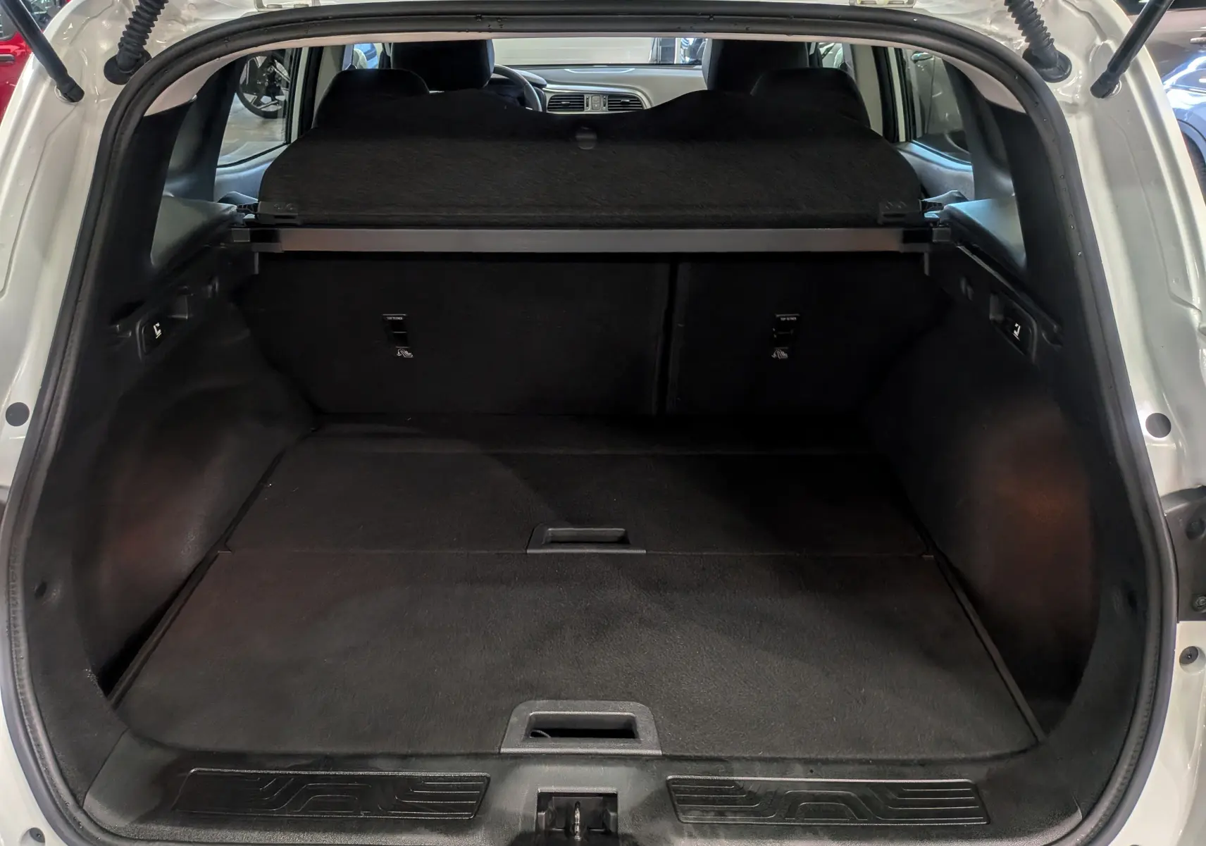 Coffre ouvert vu de l'arrière d'un Renault Kadjar Blanc Glacier 2021, avec cache-bagages et intérieur noir.