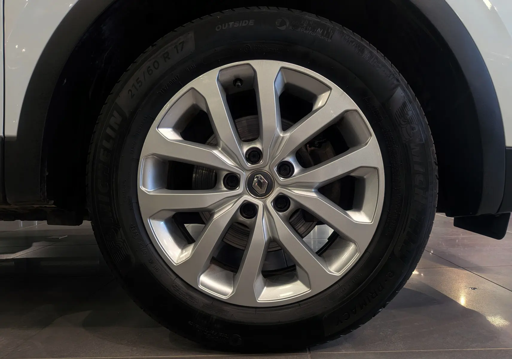 Gros plan sur la roue avant droite du Renault Kadjar blanc Glacier avec jante alliage 17 pouces et logo central Renault.