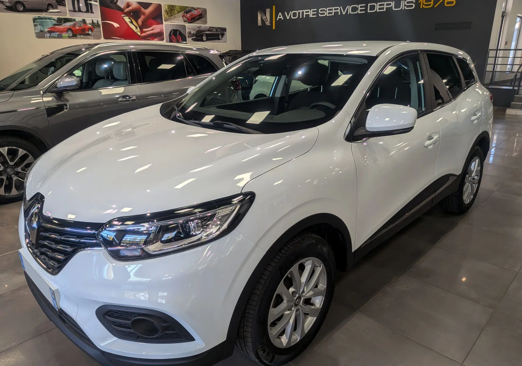 Renault Kadjar Blanc Glacier en 3/4 avant droit, SUV compact avec détails noirs et jantes alliage visibles en showroom.