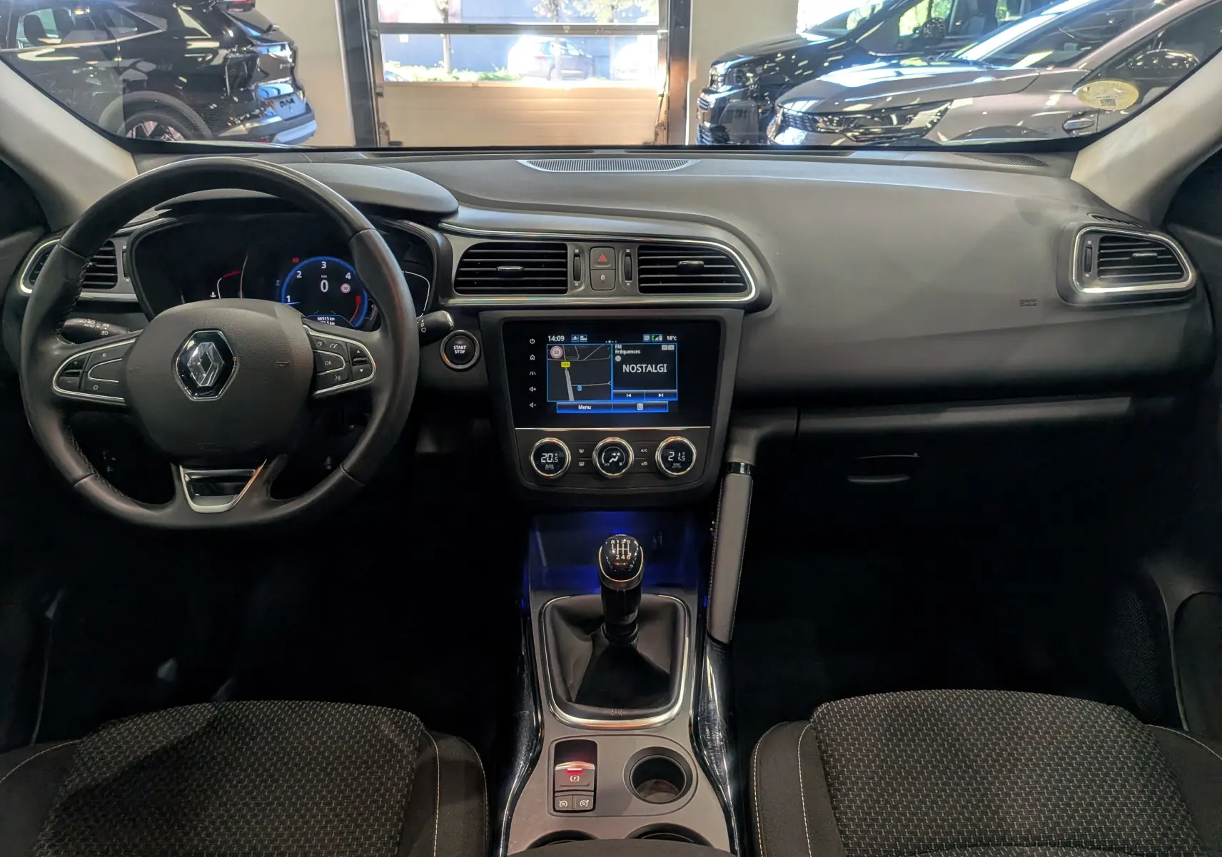 Vue intérieure frontale du tableau de bord du Renault Kadjar 2021 avec volant, écran tactile et levier de vitesses manuel.