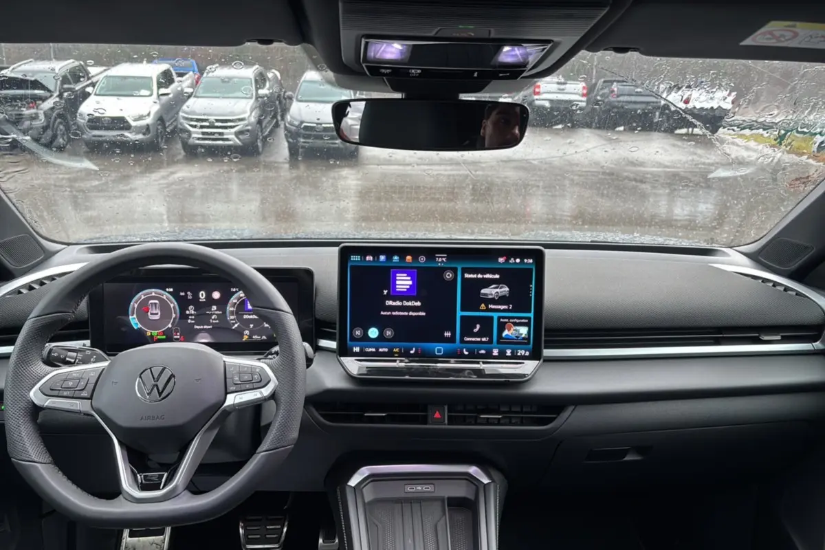 Vue intérieure frontale du tableau de bord du Volkswagen T-Roc gris loup avec écran tactile et volant multifonctions.