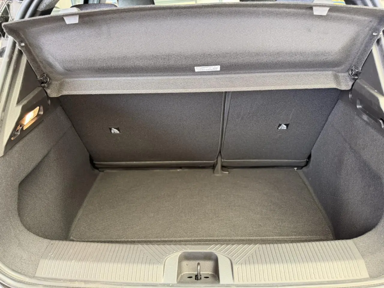 Vue intérieure du coffre ouvert de la Renault R5 E-Tech Electrique 120 noir étoilé, montrant un espace de rangement propre et vide.