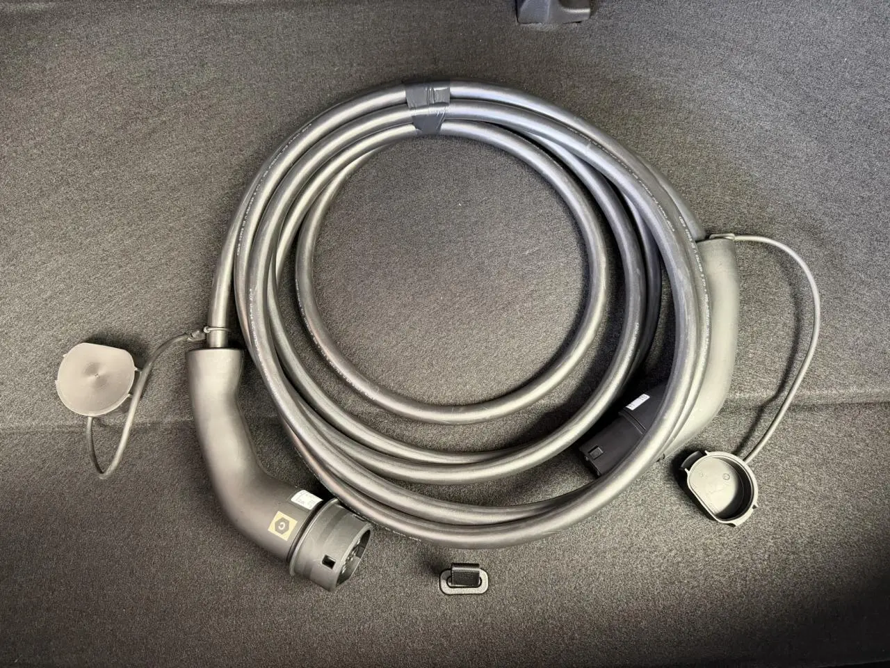 Câble de recharge électrique enroulé dans le coffre d'une Renault R5 E-Tech Noir Étoilé, vue rapprochée du câble.