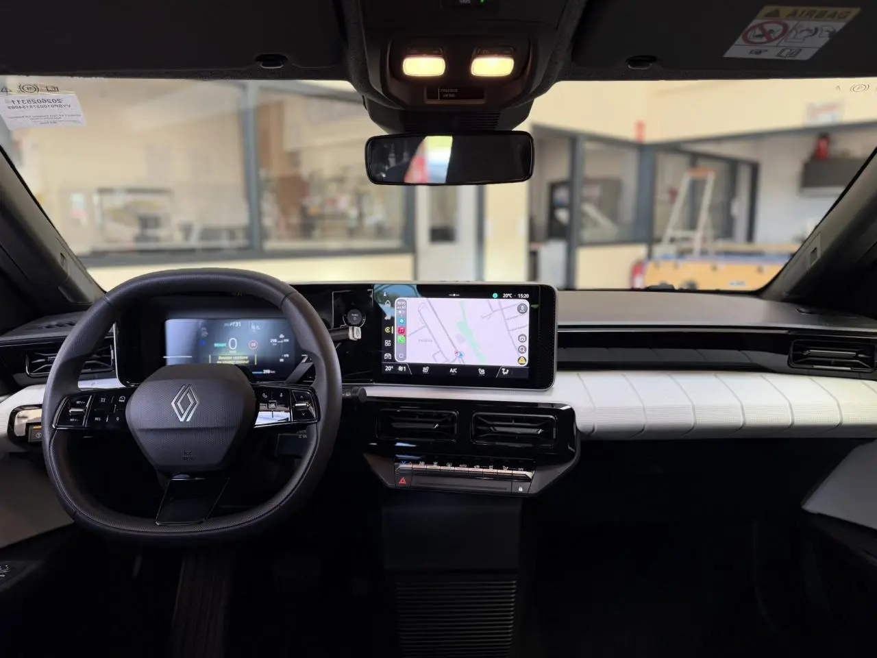 Vue intérieure frontale du tableau de bord noir et blanc de la Renault R5 E-Tech avec écran tactile et volant multifonction.