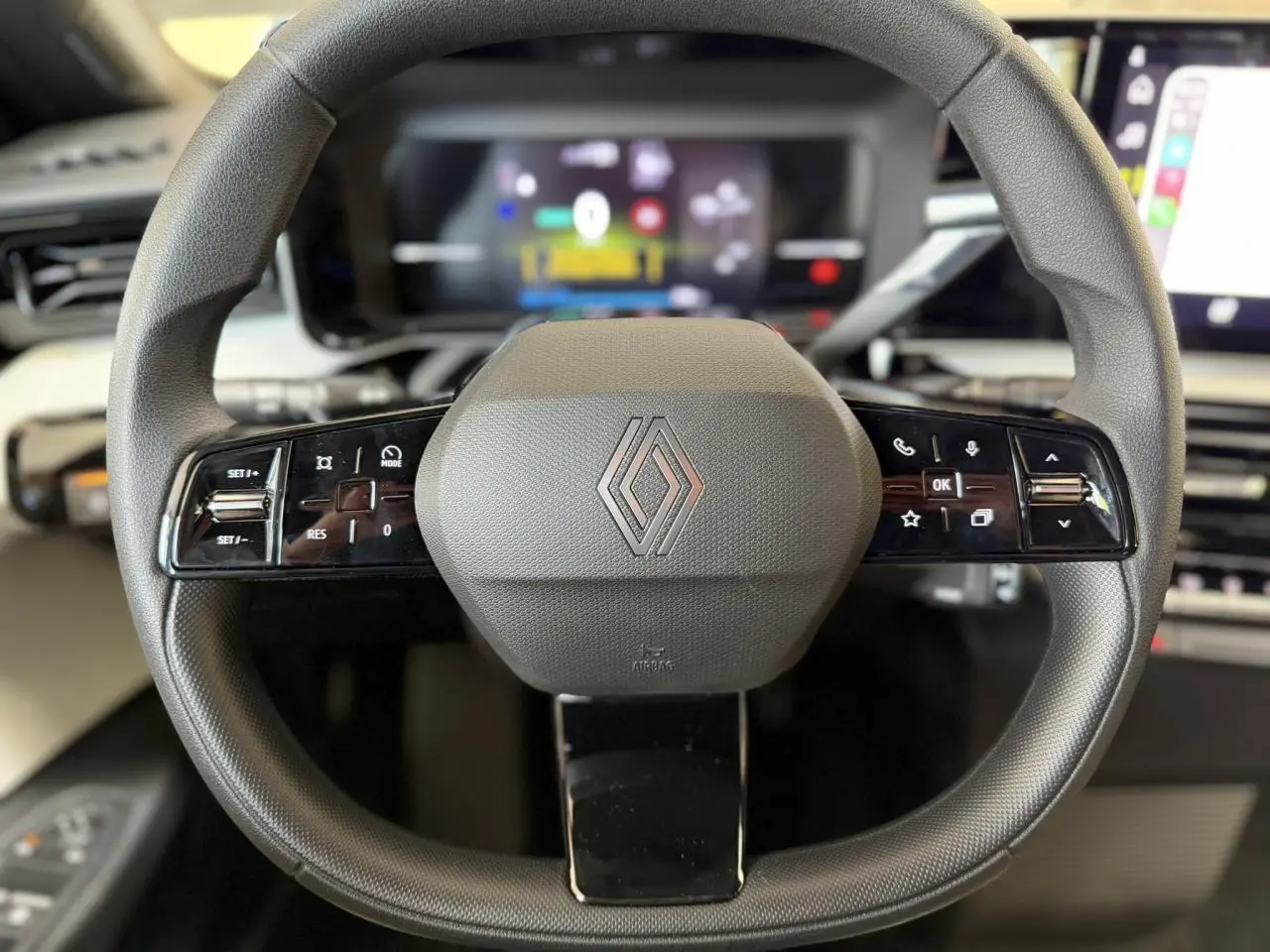 Vue rapprochée du volant noir grainé multifonction de la Renault R5 E-Tech 2026 avec logo central et commandes intégrées.