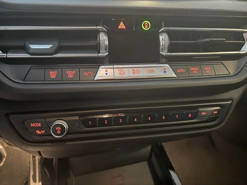 Vue rapprochée du tableau de bord de la BMW Série 1 noir métal, montrant les commandes de climatisation et la radio.