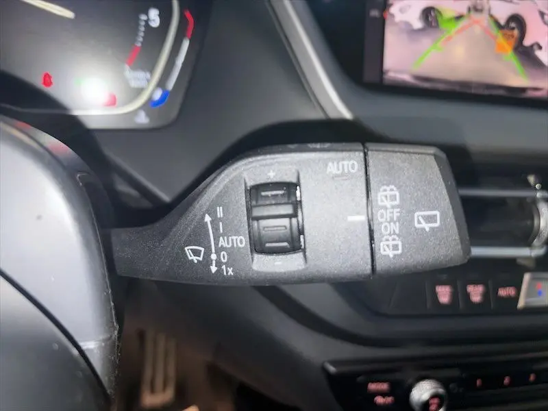 Gros plan sur la commande d’essuie-glace à gauche du volant dans l’habitacle d’une BMW Série 1 noire 2020.