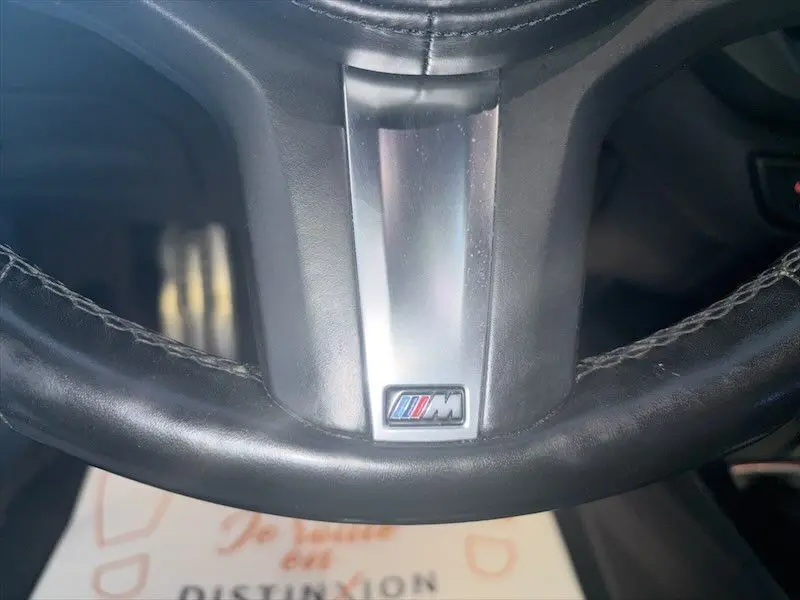 Gros plan sur le volant en cuir noir d’une BMW Série 1 118D M Sport avec logo M au centre.