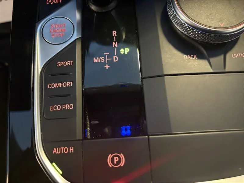 Gros plan sur la console centrale de la BMW Série 1 noire, montrant le levier de vitesses automatique et les boutons de modes de conduite.