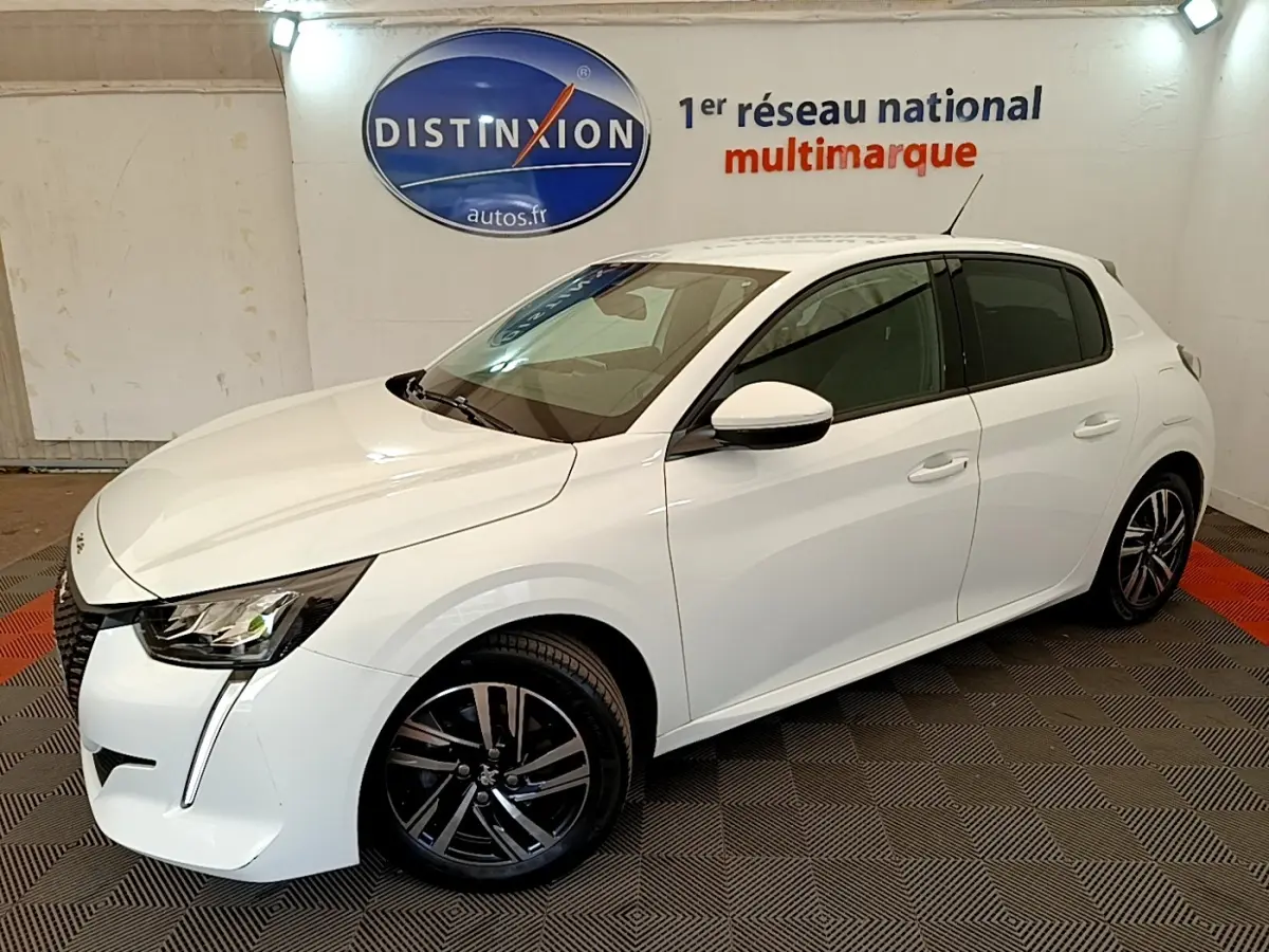 Peugeot 208 blanc vue 3/4 avant droit, avec jantes alliage noires et phares LED distinctifs.