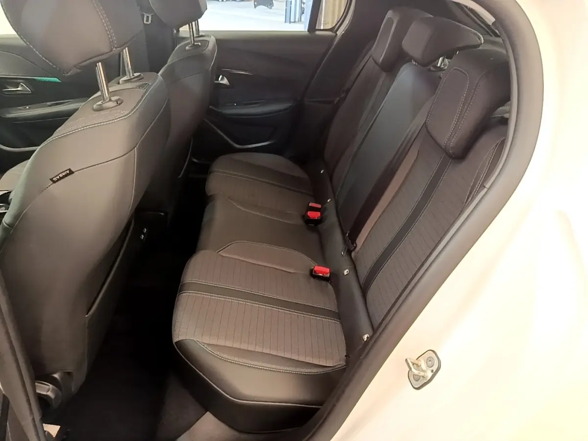 Vue intérieure côté droit montrant la banquette arrière noire et grise du Peugeot 208 blanc, avec ceintures rouges visibles.