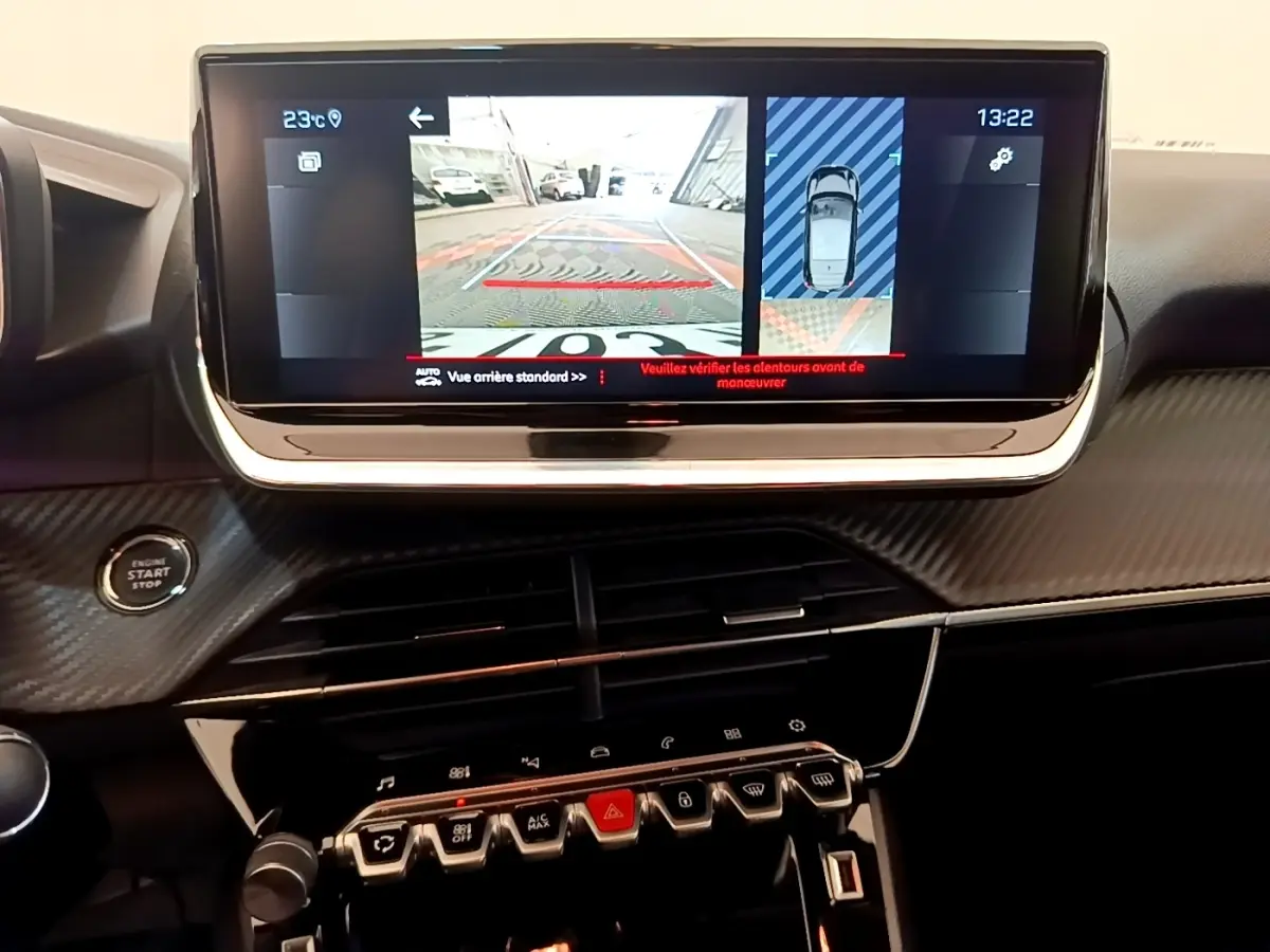 Vue rapprochée de l’écran tactile central affichant la caméra de recul dans l’habitacle noir d’une Peugeot 208 blanche.