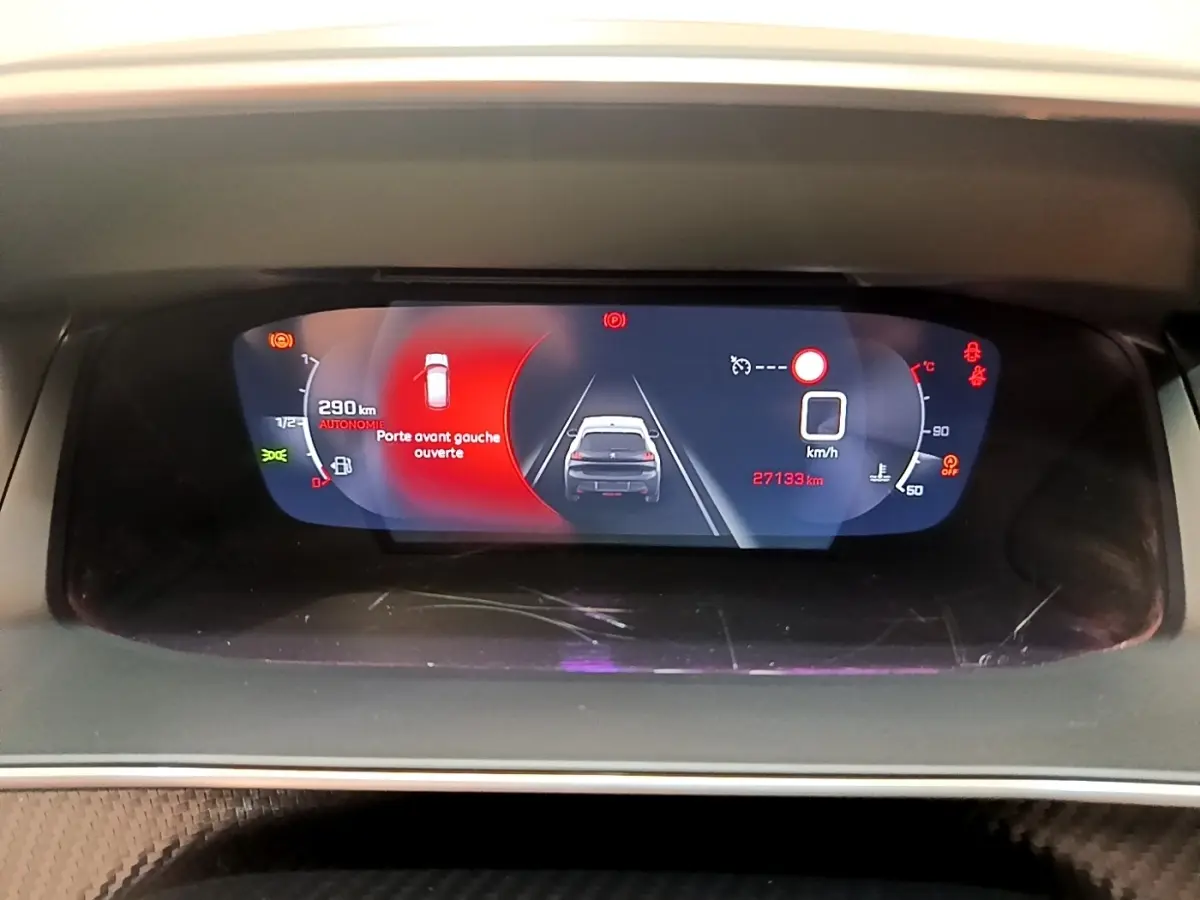 Vue rapprochée du tableau de bord numérique de la Peugeot 208 blanc, affichant une porte avant gauche ouverte et 27 193 km au compteur.