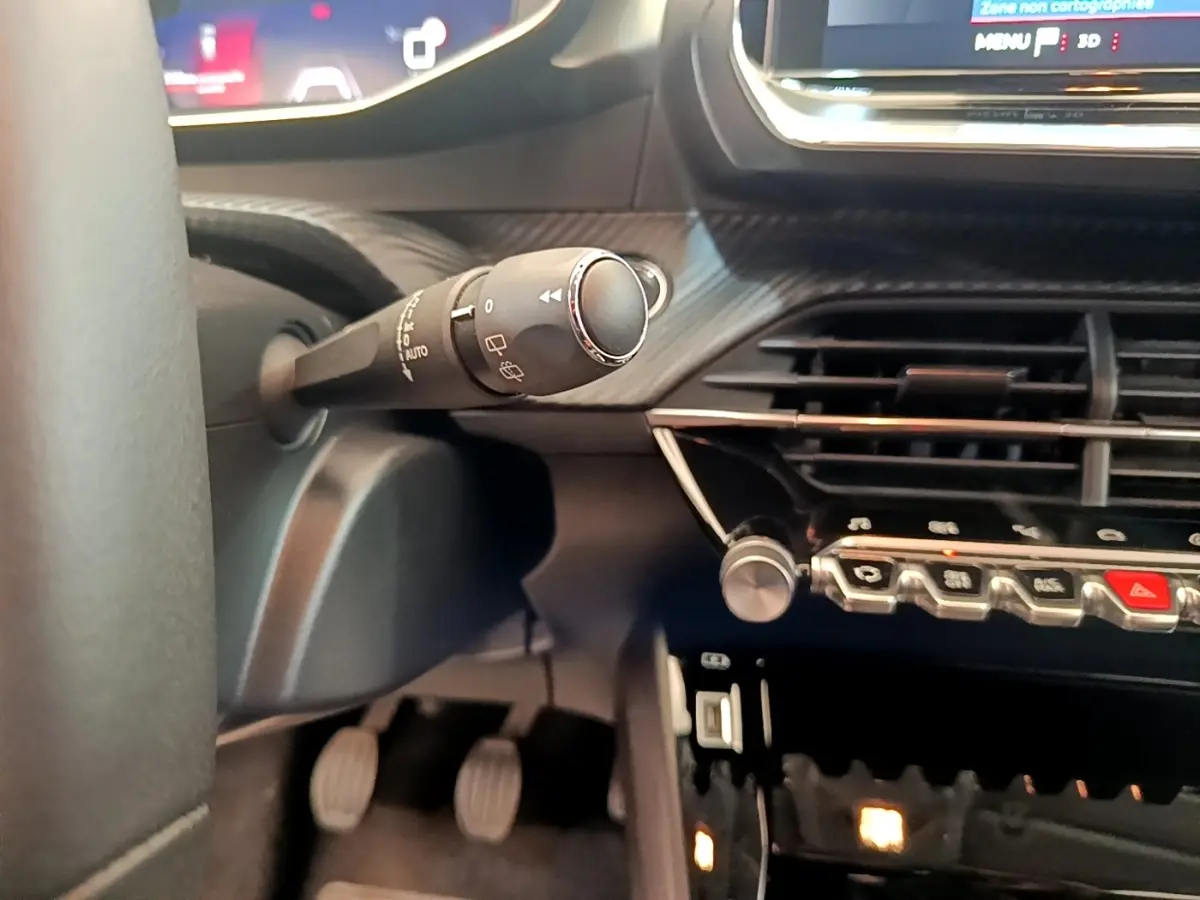 Gros plan sur la commande d’essuie-glace et la console centrale noire du tableau de bord de la Peugeot 208 PureTech 100.