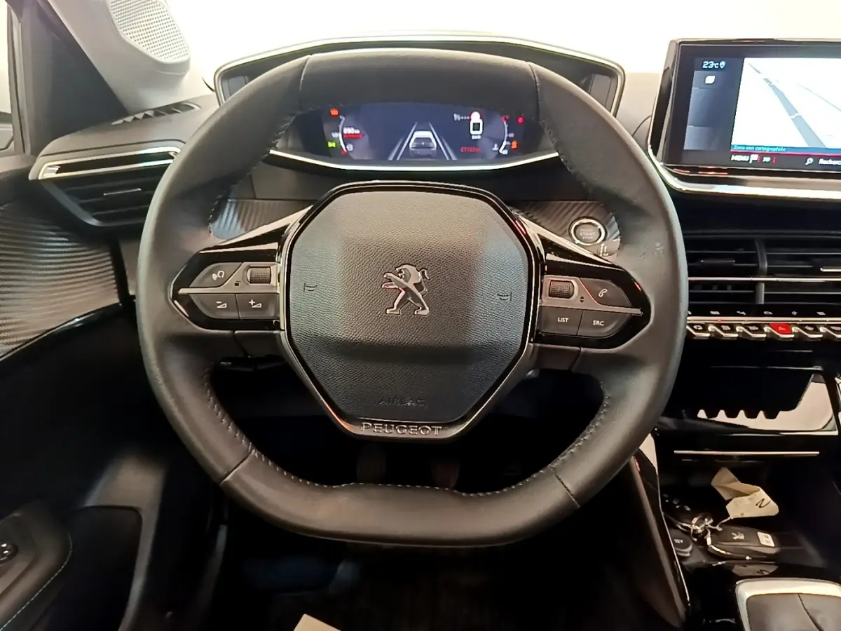 Vue intérieure centrée sur le volant cuir noir de la Peugeot 208 avec tableau de bord numérique et écran tactile de navigation.
