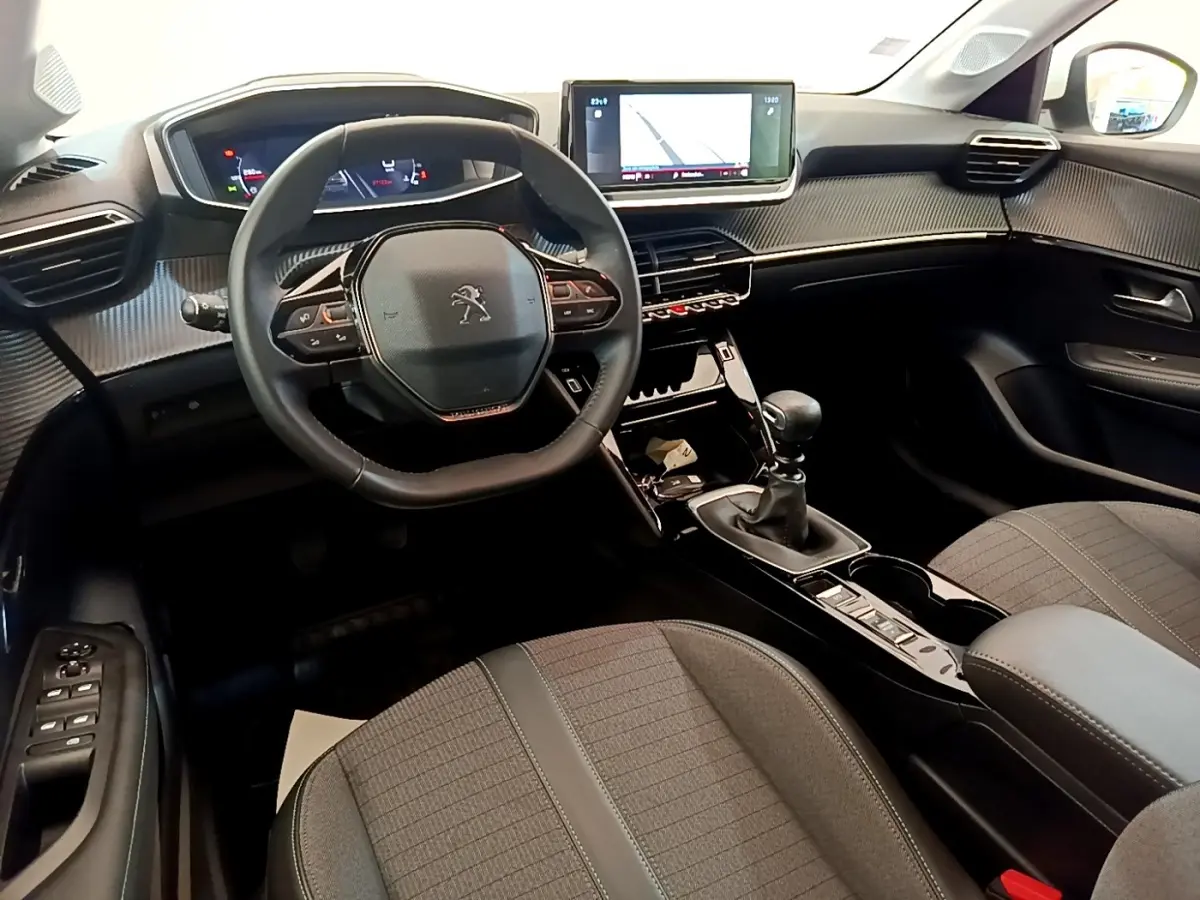 Vue intérieure avant de la Peugeot 208 blanche, avec volant cuir, écran tactile 10 pouces et boîte manuelle.