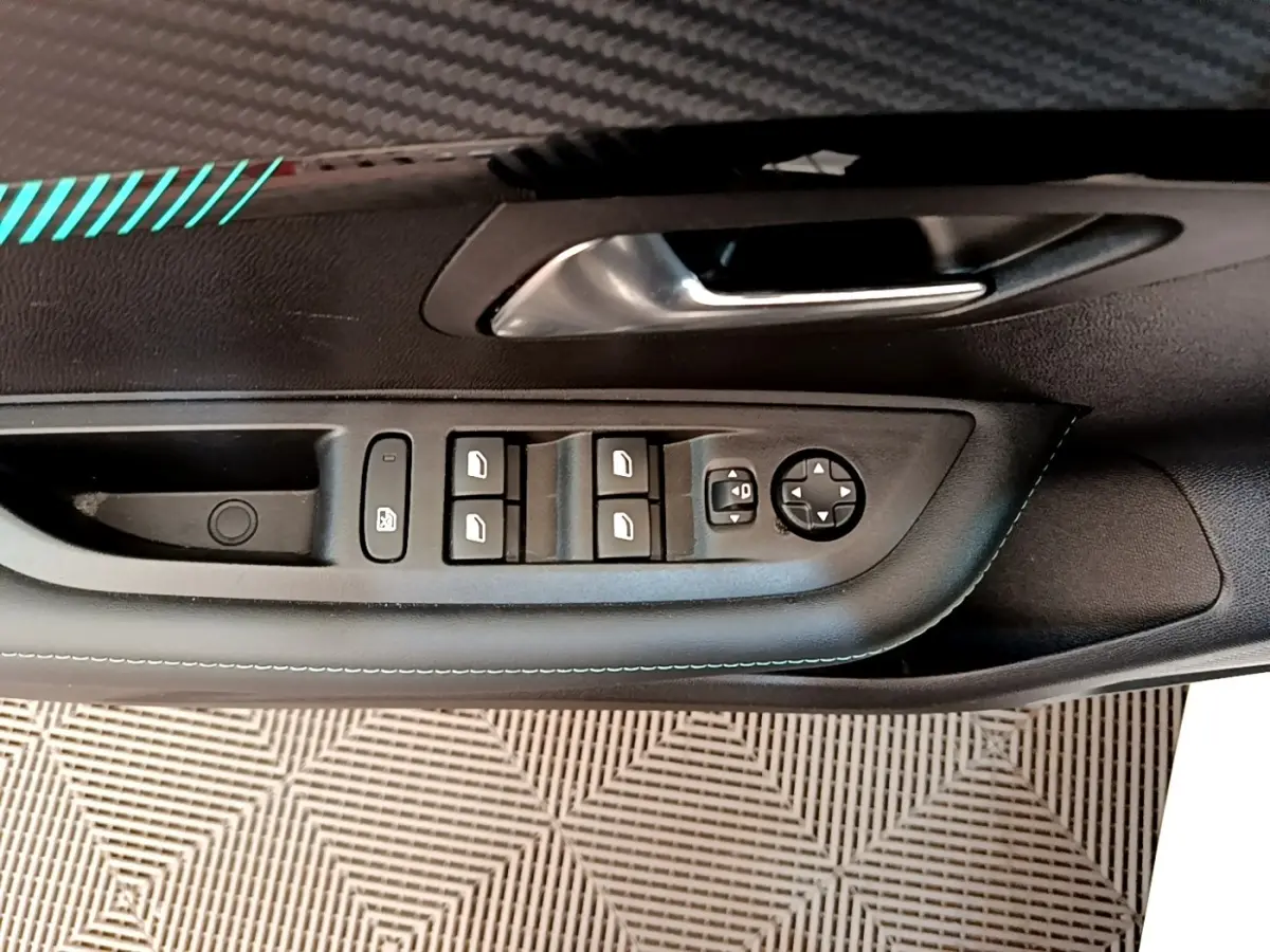 Vue rapprochée de la porte avant gauche de la Peugeot 208 blanche, montrant les commandes des vitres et rétroviseurs.