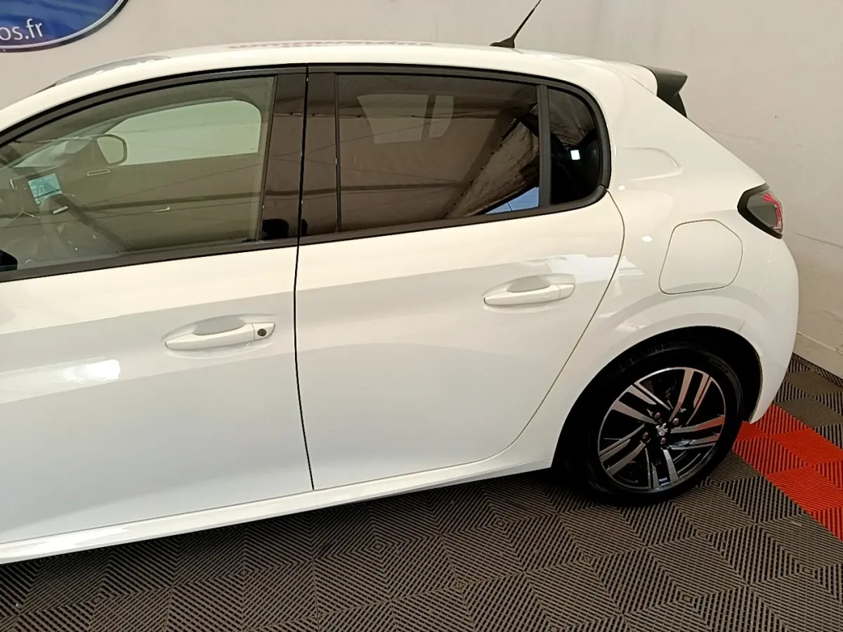 Vue latérale droite d'une Peugeot 208 blanche 2021 avec jantes alliage et vitres teintées.