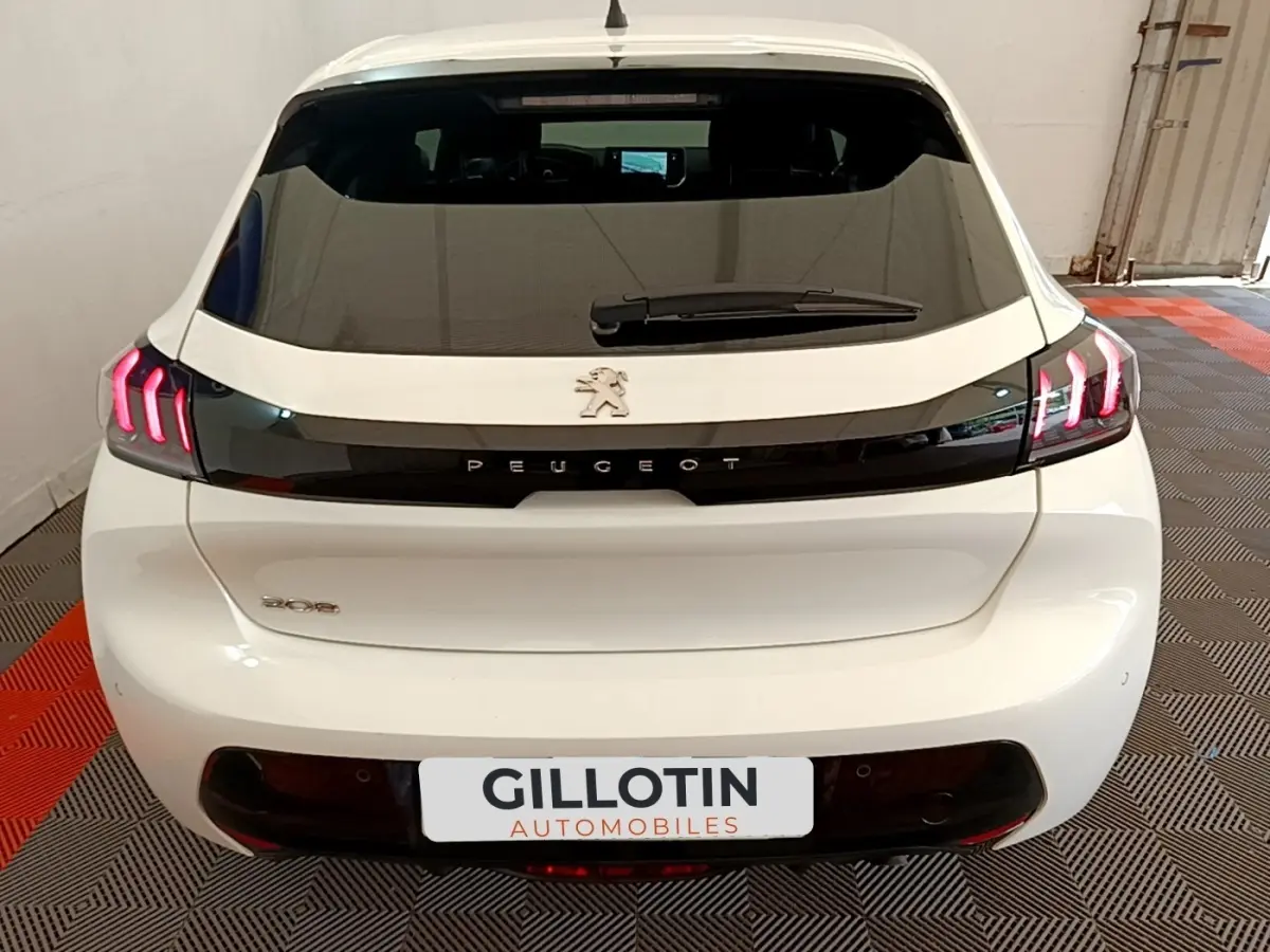 Vue arrière d'une Peugeot 208 blanche avec feux arrière LED en forme de griffes et logo Peugeot noir brillant.