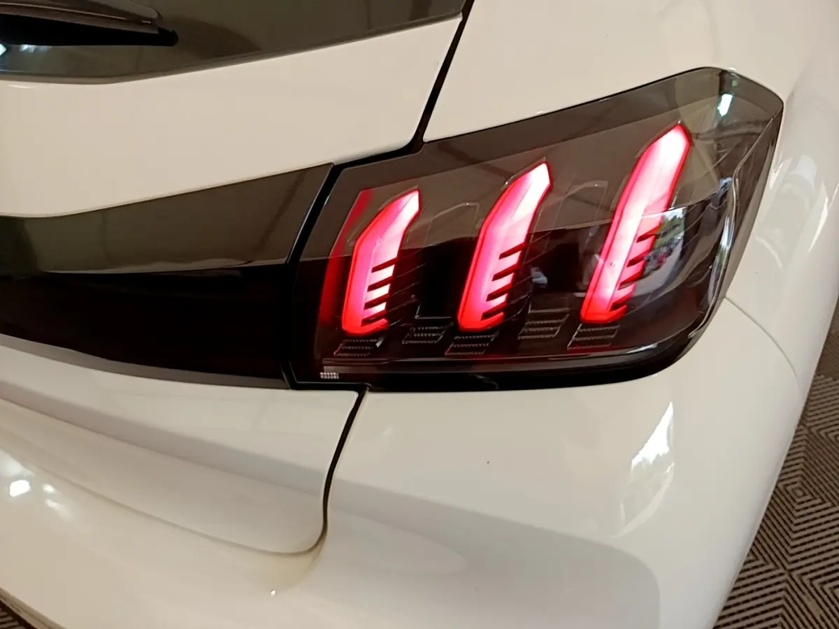 Gros plan sur le feu arrière droit rouge de la Peugeot 208 blanche PureTech 100 S&S Allure Business de 2021.