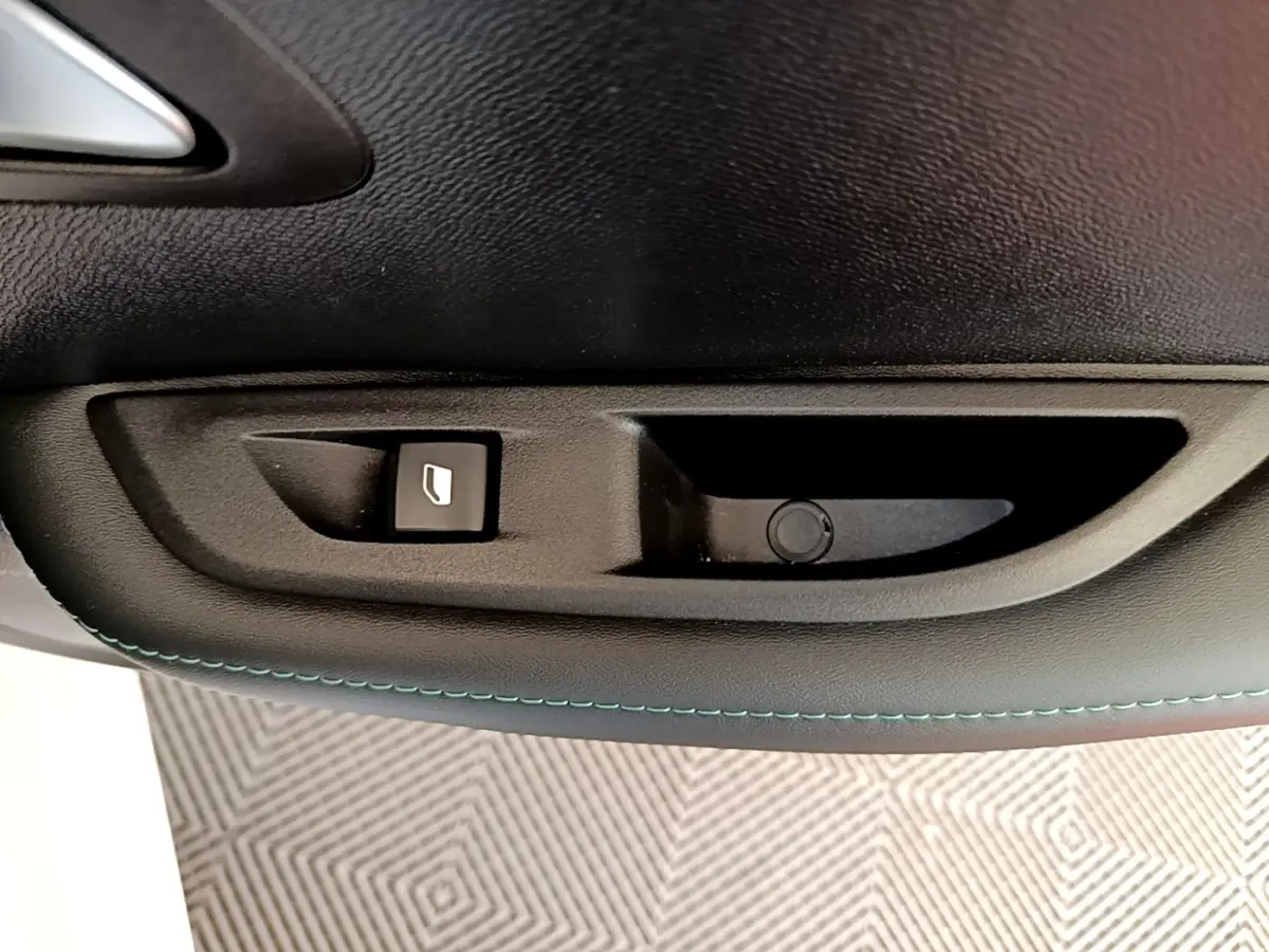 Gros plan sur la commande de lève-vitre côté gauche d’une Peugeot 208 blanche, finition Allure Business.