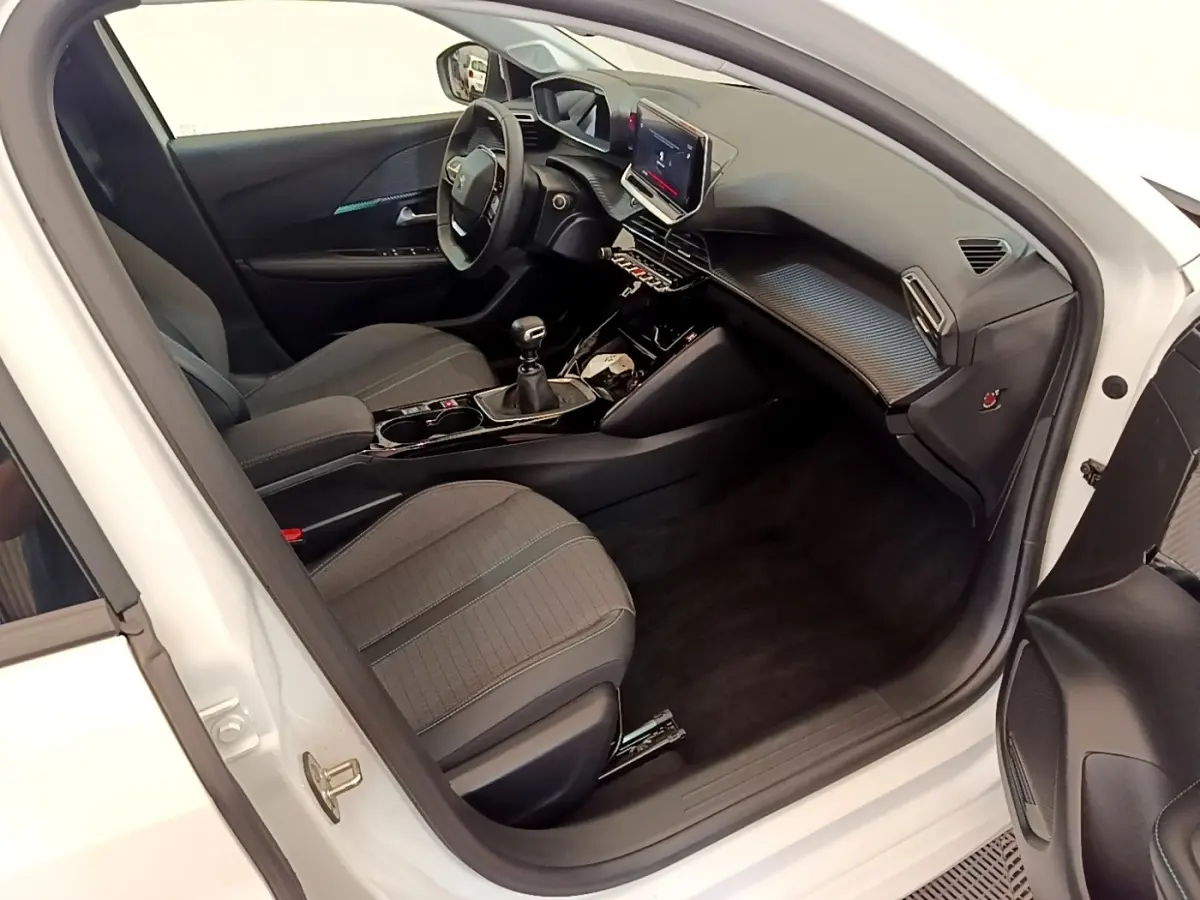Vue intérieure côté conducteur de la Peugeot 208 blanche, mettant en valeur le tableau de bord et l’écran tactile 10 pouces.