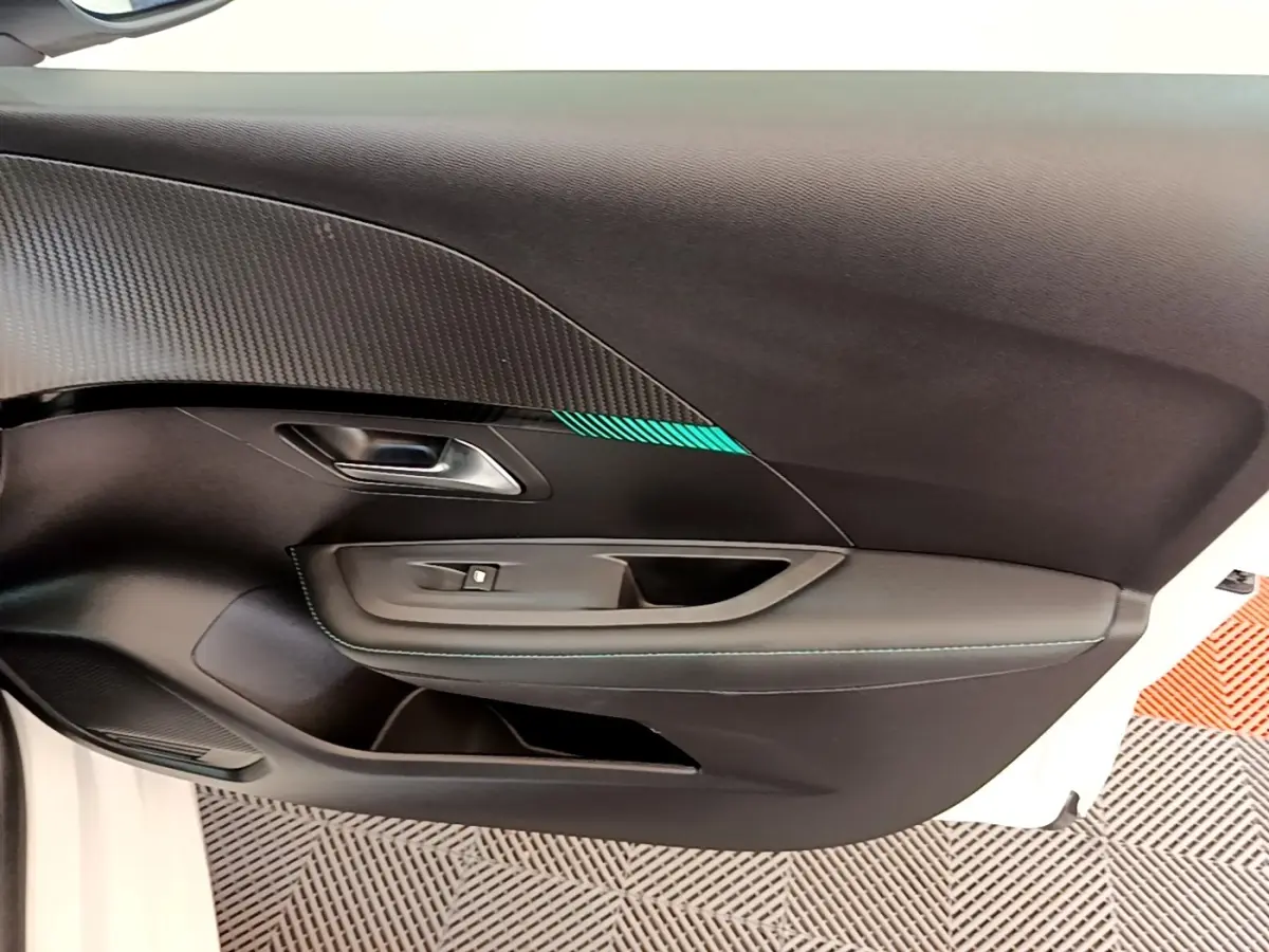 Vue intérieure côté gauche de la porte avant d'une Peugeot 208 blanche avec insert décoratif et surpiqûres bleues.