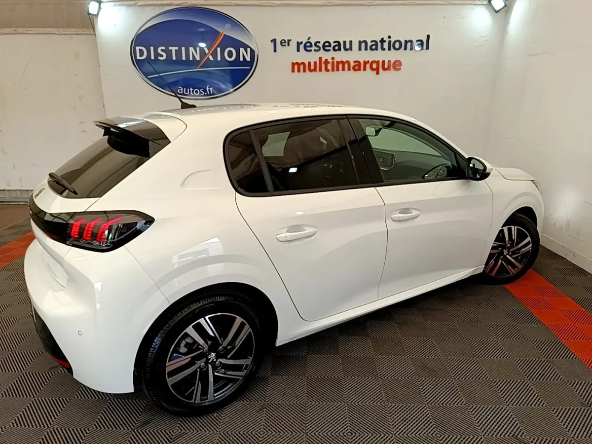 Peugeot 208 blanc vue 3/4 arrière droit, feux arrière LED griffés et jantes alliage noires et argentées.