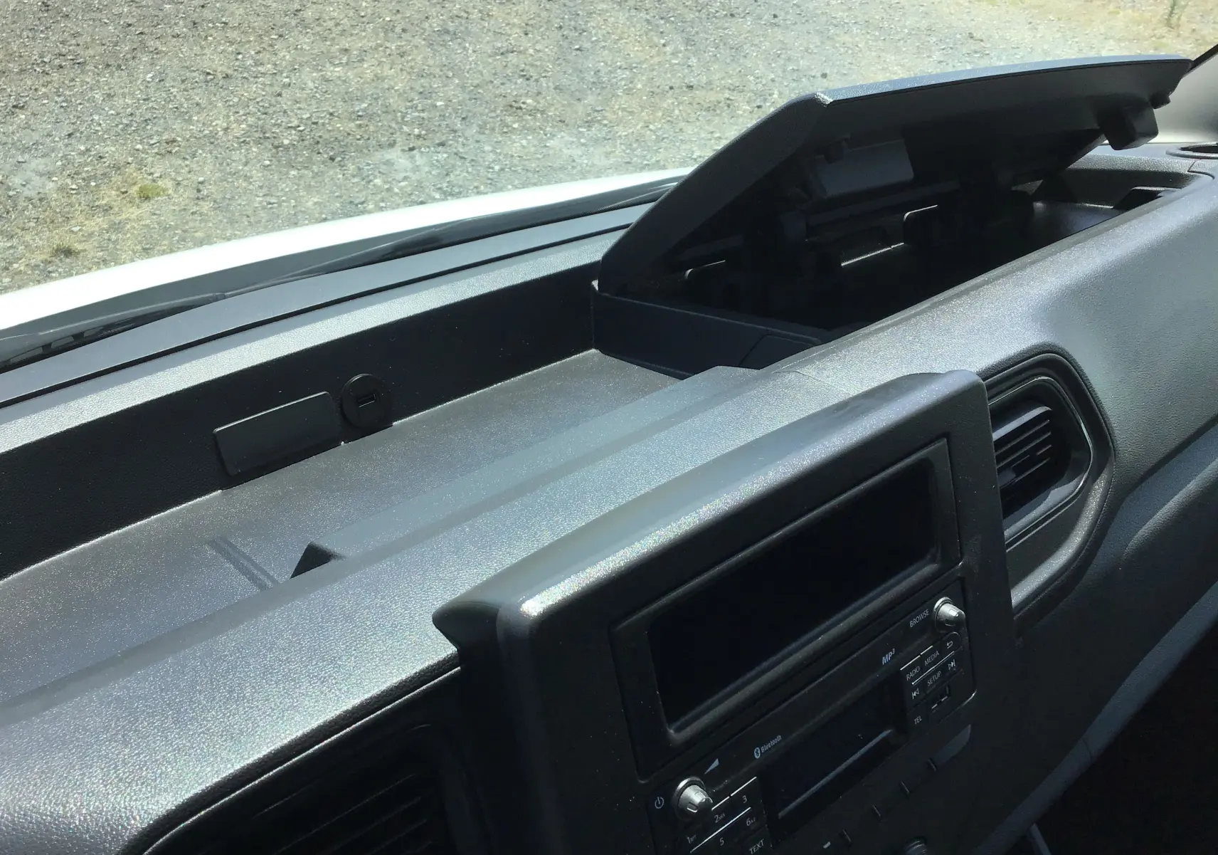 Vue rapprochée de la planche de bord noire du Renault Master Châssis Cabine blanc, avec boîte à gants ouverte.