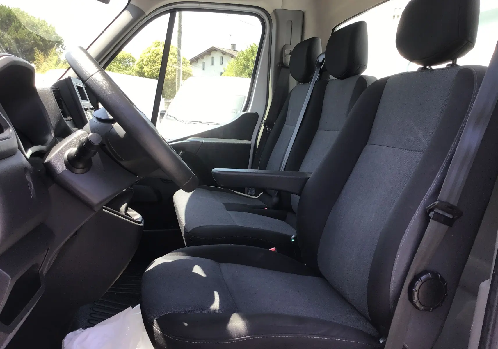 Vue intérieure côté conducteur du Renault Master Châssis Cabine 2024, montrant les sièges gris foncé et le volant noir.