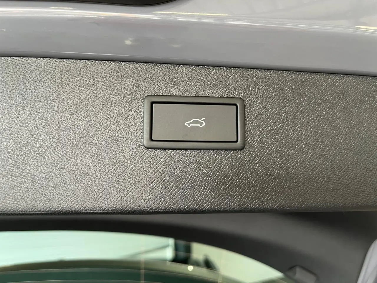 Bouton d'ouverture électrique du hayon sur la garniture intérieure du coffre du CUPRA Formentor gris clair.